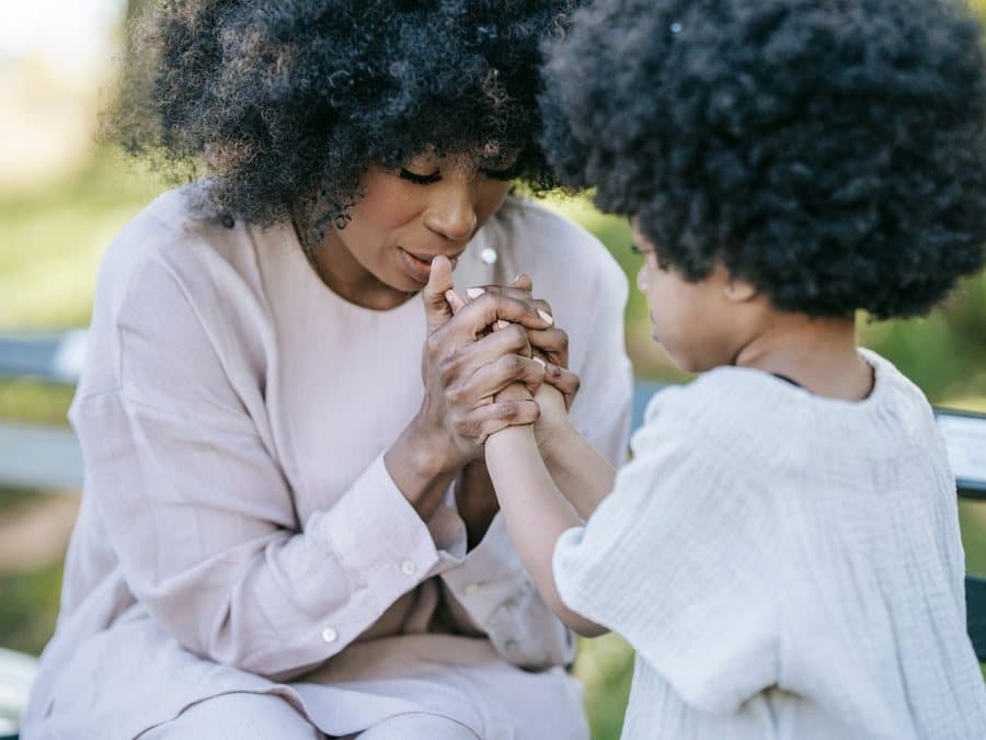 Les mains d’une mère et de son enfant réunies, en extérieur, lumière douce